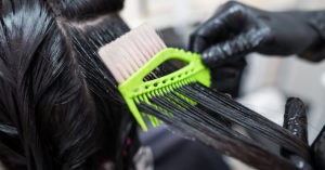 A hairstylist applying hair straightener to a woman hair